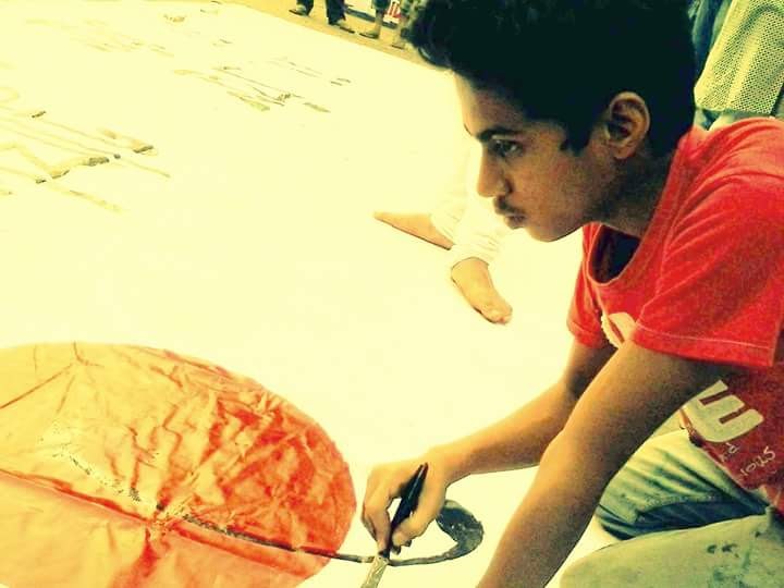 A younger Rabi painting a large poster by hand on the floor