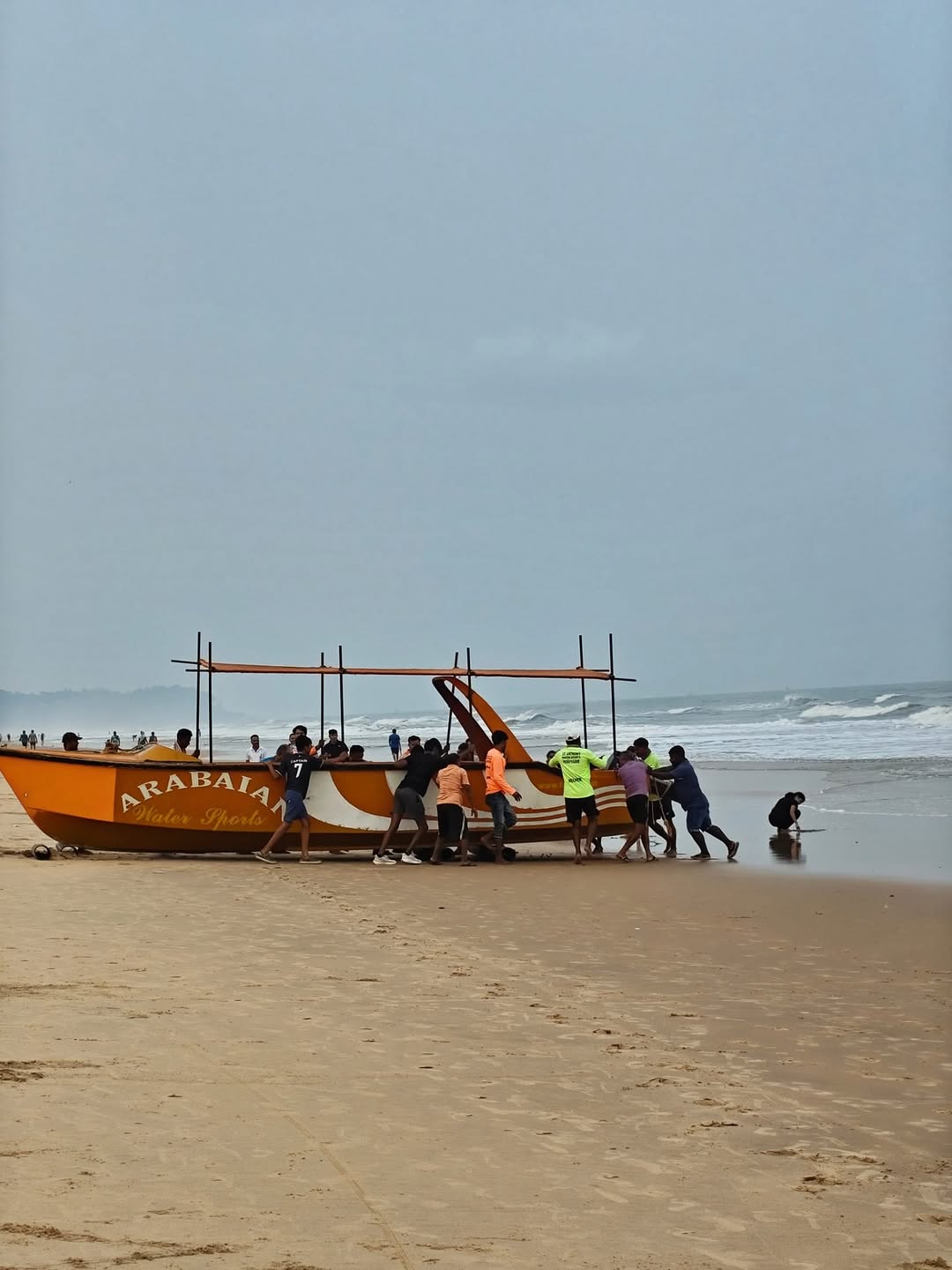 A crew pushing a boat down the sand
