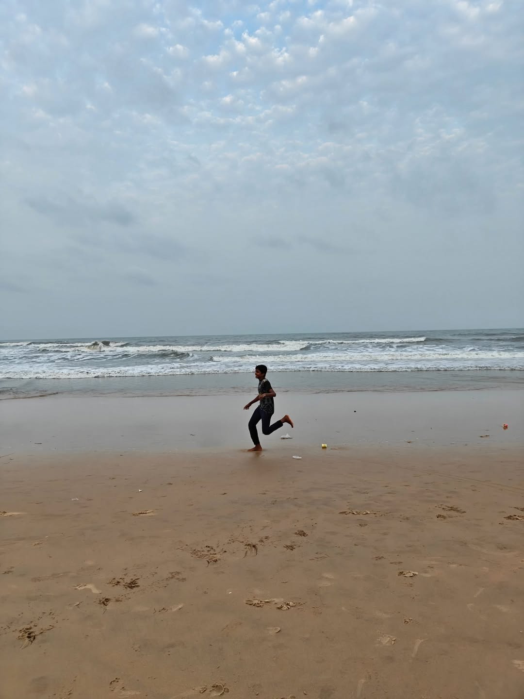 A boy running along the wet sand
