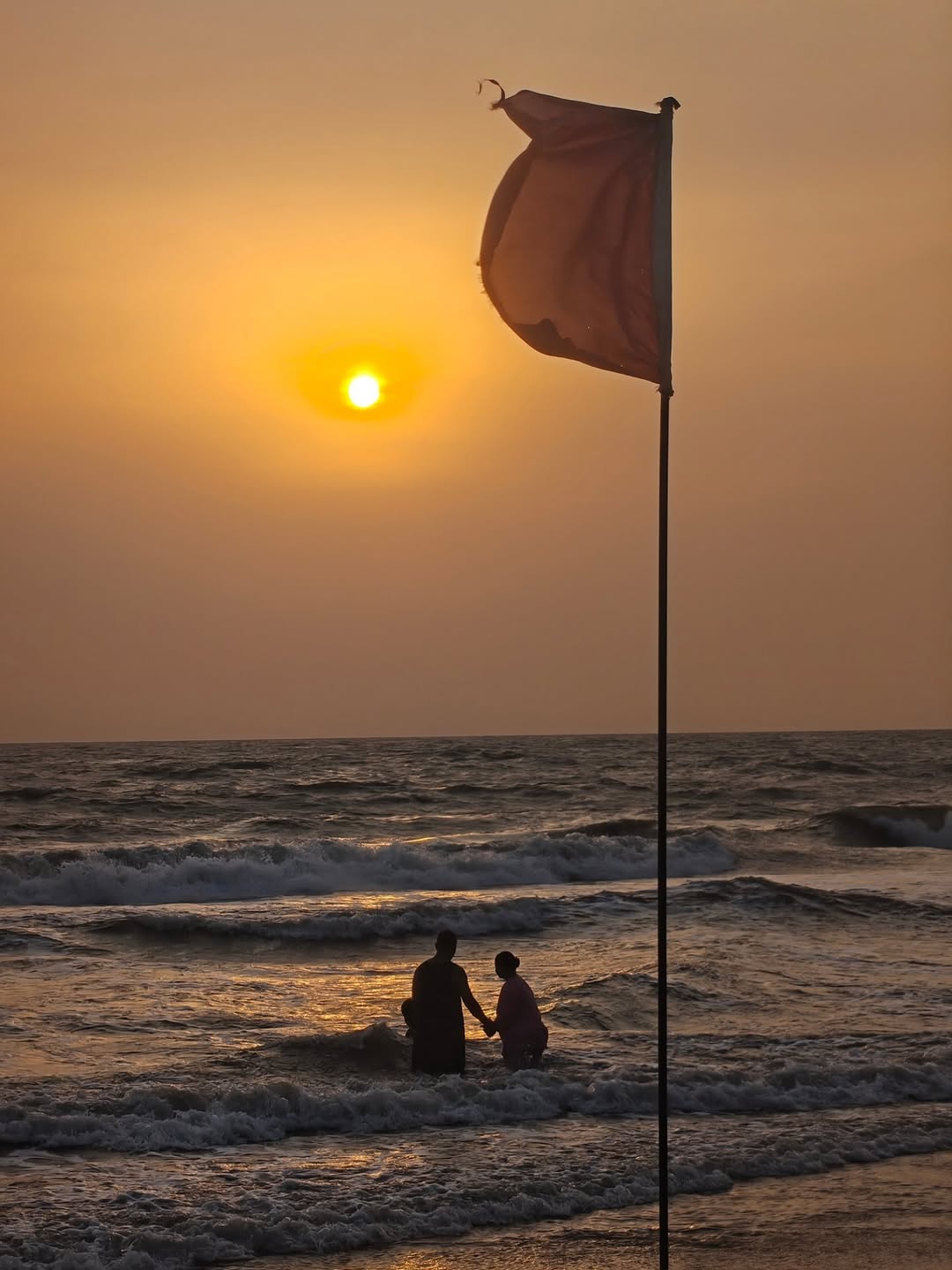 Two bathers beneath a flag at sunset